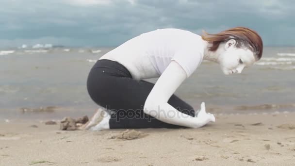 Performancekonstnär täckt av vit färg hopkrupen på sandstranden sea shore — Stockvideo