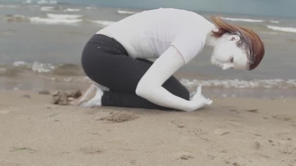 Artista ativista coberto de tinta branca agachada na costa do mar arenoso — Vídeo de Stock