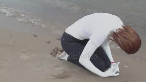 Ydeevne skuespiller dækket i hvid maling sammenkrøbet på sandstrand – Stock-video