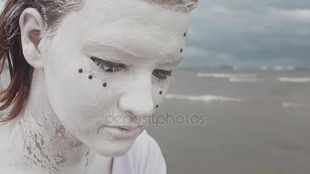 Retrato de artista de performance cubierto de pintura blanca sacudiendo la cabeza en la orilla del mar — Vídeos de Stock