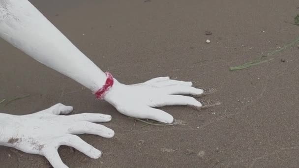 Руки художньої дівчини вкриті білою фарбою пасує мокрий пісок на морському березі — стокове відео