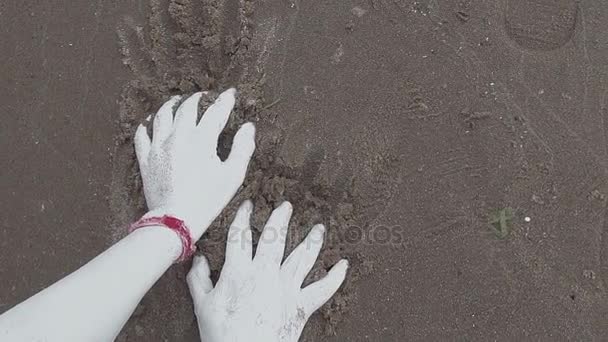 Handen van artistieke vrouwelijke bedekt met witte verf pakt nat zand op zee — Stockvideo