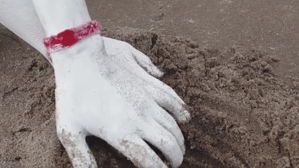 Művészi személy borított fehér festékkel ága megragadja a nedves homok, a tenger partján — Stock videók