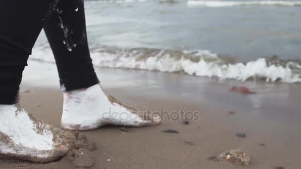 Fötter av konstnärliga flicka täckt av vit färg steg på våt sand vid havets strand — Stockvideo