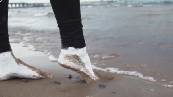 Pés de mulher artística coberta de pisos de tinta branca na areia molhada na costa do mar — Vídeo de Stock