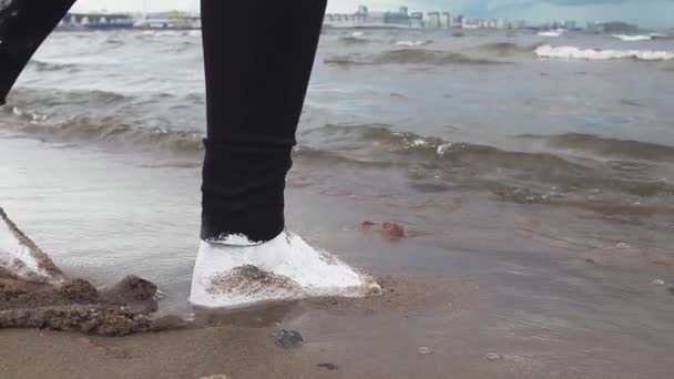 Fötter av konstnärlig kvinna täckt av vit färg steg på våt sand vid havets strand — Stockvideo
