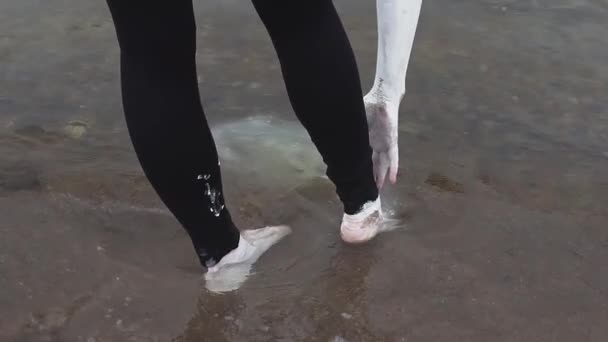 Kunstnerisk person dækket i hvid maling strækker sig til tæer stående i havvand – Stock-video