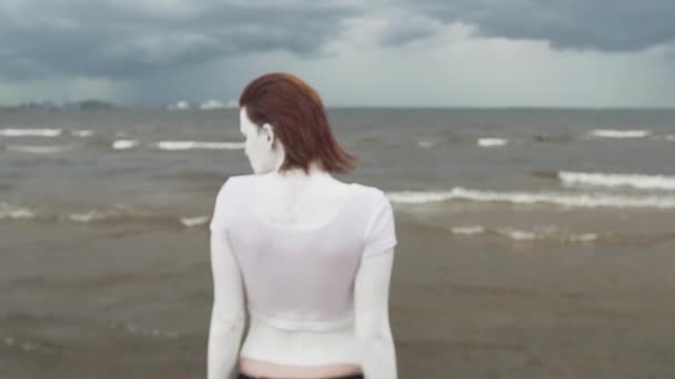 Vissza a művészi nő borított fehér festékkel állandó tenger partján — Stock videók