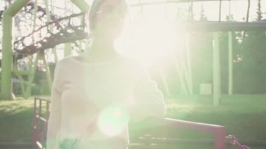 Genç ve güzel Kız bardaklarda parlak güneş ışını lunapark treni yakınında duran