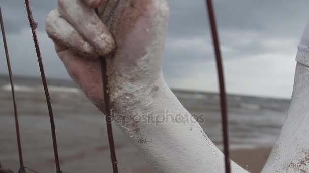 Performance-Künstlerin mit weißer Farbe bedeckte Hand greift nach Metallstangen — Stockvideo