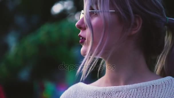 Όμορφη νεαρή κοπέλα σε ποτήρια θέτοντας σε πάρκο διασκέδασης που κοντά σε αξιοθέατα — Αρχείο Βίντεο