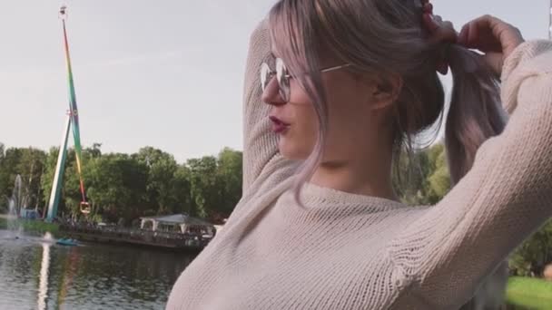 Atractiva joven chica haciendo cola de caballo cerca del estanque en el parque de atracciones — Vídeos de Stock