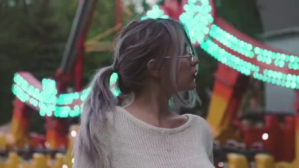 Menina bonita em óculos de pé perto da atração swing no parque de diversões — Vídeo de Stock