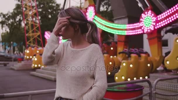 Attractive girl in glasses caress hair near swing attraction in amusment park — Stock Video