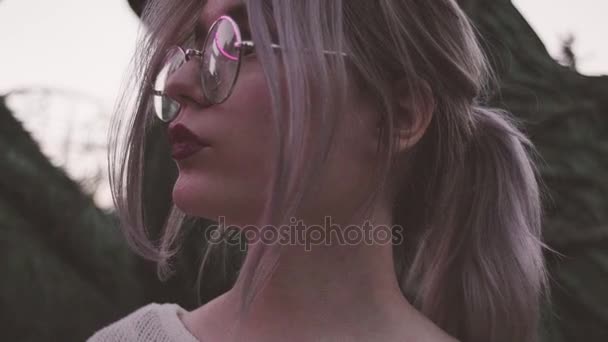 Красивая девушка в очках позирует для портрета в мигающих огнях — стоковое видео