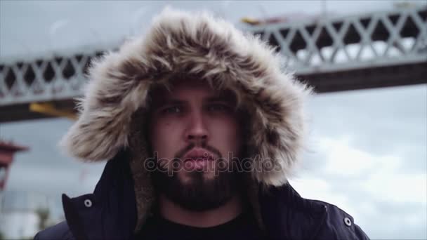 Young bearded guy in hooded parka walking toward camera — Stock Video