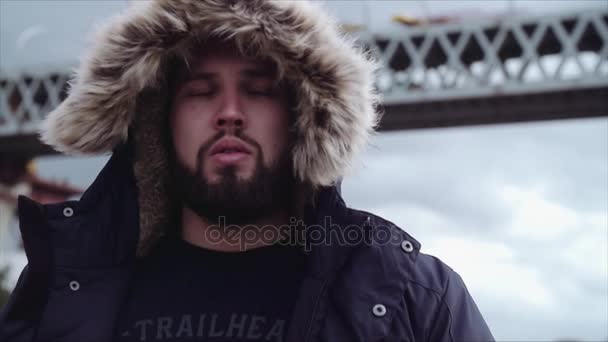 Well-groomed bearded guy in hooded parka walking toward camera — Stock Video