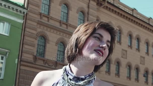 Красивая девушка счастливо улыбается в старом городе в летнем платье — стоковое видео