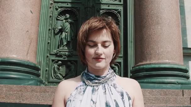 Chica bonita en vestido de verano posando frente a la vieja puerta de la iglesia ortodoxa — Vídeos de Stock