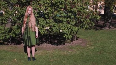 Uzun saçlı Kızıl saçlı genç kız Park bush ayakta