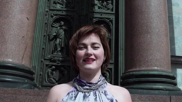 Hübsche Frau im Sommerkleid lächelt vor alter orthodoxer Kirchentür — Stockvideo