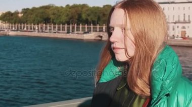 Uzun saçlı Kızıl saçlı güzel kız şehir nehir köprüsü arasında yürüyüş