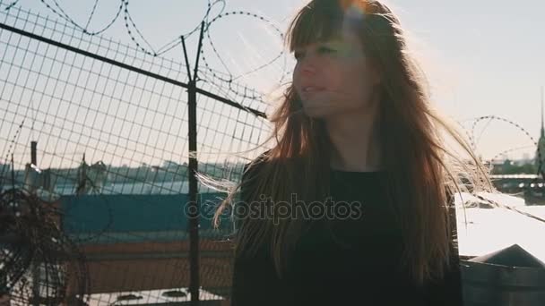 Piękna młoda kobieta w czarnej sukience na dachu z widokiem na malownicze miasto rzeki — Wideo stockowe