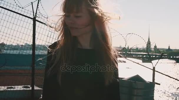Csinos, fiatal nő, fekete ruhás, a város festői folyóra néző tetőtéri — Stock videók