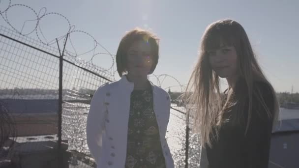 Dos chicas muy jóvenes en la azotea con vistas panorámicas al río de la ciudad — Vídeos de Stock