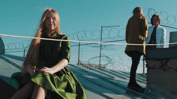 Longhaired ginger young girl with friends sitting on roofing with barb wire — Stock Video