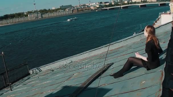 Cute młoda dziewczyna w czarnej sukni siedzi na pokrycia dachowe z malowniczą panoramę miasta — Wideo stockowe