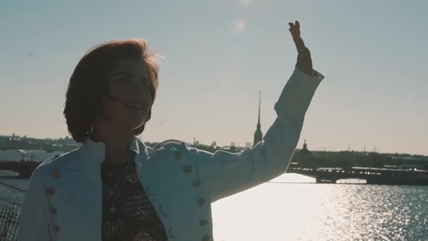 Mooie jonge meisje in witte jas op dakterras met uitzicht op rivier de schilderachtige stad — Stockvideo