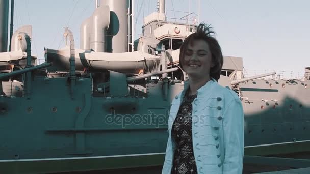 Радісна дівчина в літній сукні посміхається перед старим музеєм лінкорів — стокове відео