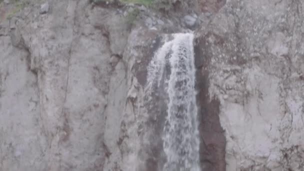 Каскад воды стекает вниз по скалистой скале в горах — стоковое видео