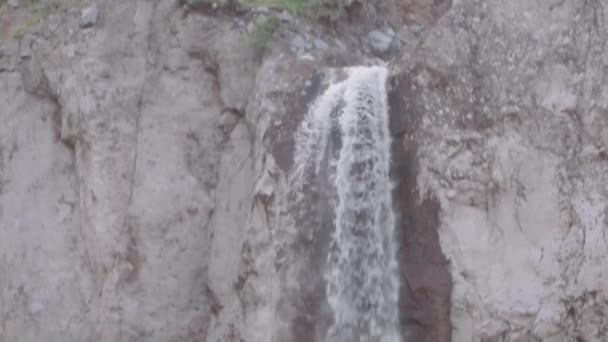 Wasserfall fließt über felsige Klippe in die Berge — Stockvideo