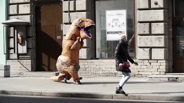 SAINT PETERSBURG, RUSSIA - 1 APRILE 2017: Prankster in costume da dinosauro in folla di persone che camminano sul marciapiede della città — Video Stock