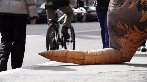 SAINT PETERSBURG, RÚSSIA - 1 de abril de 2017: Pedastrians pisa sobre a cauda do mascote de traje t rex na calçada da cidade — Vídeo de Stock