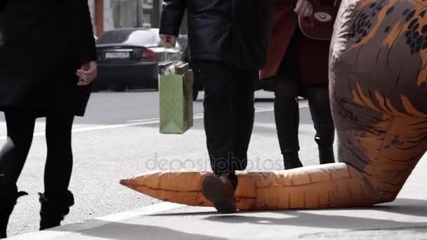 SAINT PETERSBURG, RUSSIA - 1 APRILE 2017: Pedastriani calpesta la coda della mascotte del costume da dinosauro sul marciapiede della città — Video Stock