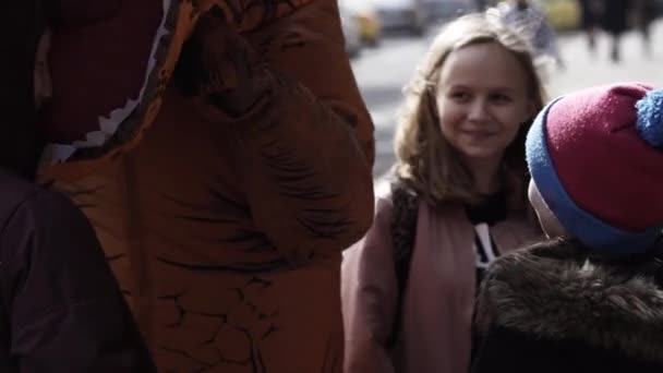 SAN PETERSBURG, RUSIA - 1 DE ABRIL DE 2017: Persona con traje de mascota de dinosaurio bromeando a los niños en la acera — Vídeos de Stock