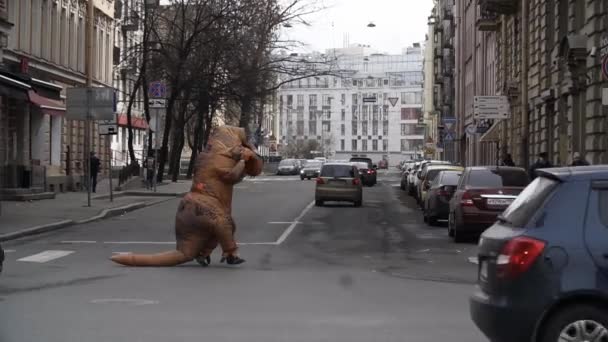 Sankt Petersburg, Ryssland - den 1 April 2017: Person i t rex kostym upptågsmakare som körs vid staden gatan övergångsställe — Stockvideo