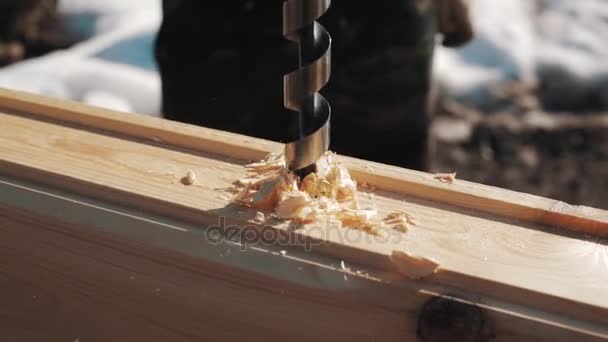 Ausbohren eines großen Lochs in einem Holzblock, wodurch im Winter draußen Sägemehl entsteht — Stockvideo