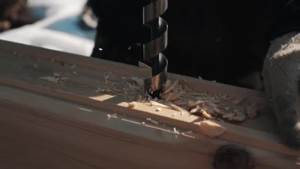 Vrták vytáhl velkou díru v dřevěných bloků, vytváření piliny venku v zimě — Stock video