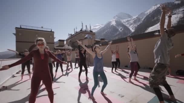SOCHI, RUSIA - 31 DE MARZO DE 2016: Grupo de personas hacen yoga en el patio al aire libre en la mañana soleada, levanten la mano. Saludable. Montañas . — Vídeos de Stock