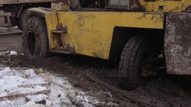 Forklift şaşırıp kalmış içinde derin çamur önünde yürüyen işçiler