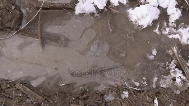 POV άνθρωπος πόδια σε πάγο διαλείμματα εκκίνησης στο λασπωμένο λακκούβα — Αρχείο Βίντεο