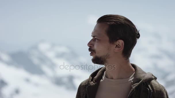 Giovane viaggiatore barbuto al pinnacolo di montagna con vista panoramica occhi strabici, parlare — Video Stock