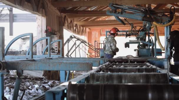 Woodworker in helmet cutting wood piece on industrial saw workbench — Stock Video