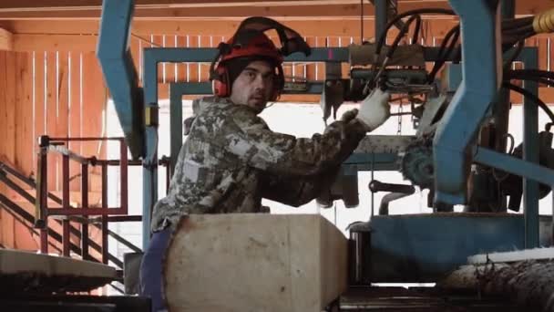 Falegname in casco tronco taglio legno su banco da lavoro sega industriale — Video Stock