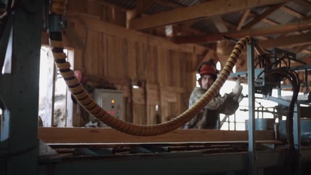 Плотник в каске пиломатериалы бревно на промышленный пильный станок — стоковое видео