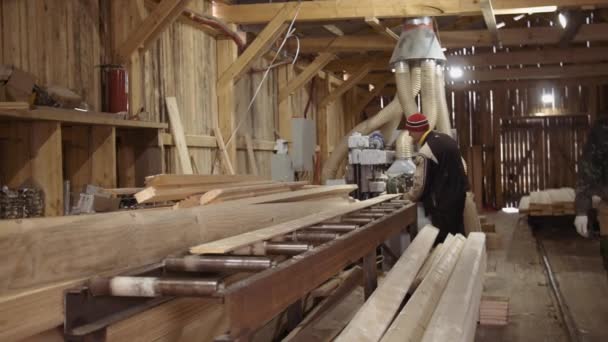 Les travailleurs ramassent la planche en train d'épuiser la machine de menuiserie à la scierie — Video